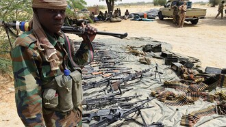 Un militar chadiano junto a un alijo de armas incautadas a Boko Haram