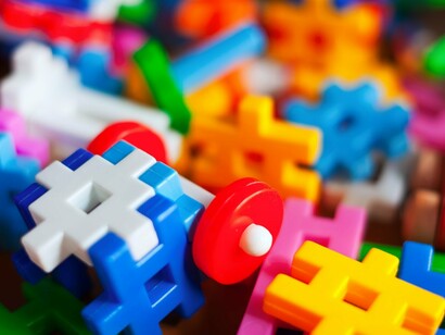 A collection of interlocking LEGO-like pieces viewed up close, reflecting how creation emerges through small actions