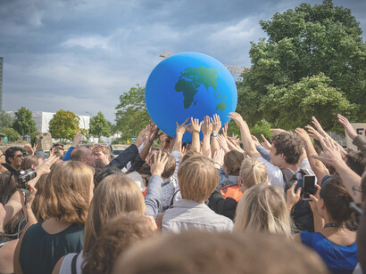 Protesters march through the streets holding a large inflatable Earth ball to highlight global solidarity and urgent action on climate change in Berlin, BE, Germany