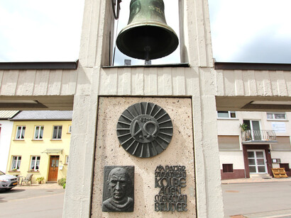 Acercamiento al monumento a Maximilian Kolbe con fuente y reloj de sol en la explanada de la iglesia de Mettendorf, Alemania