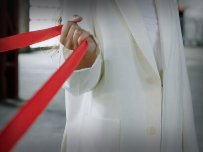 Mão puxa uma fita vermelha na tentiva de trazer algo para perto