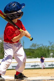 A young boy gripping his bat with determination, reflecting the early spark of competitive spirit