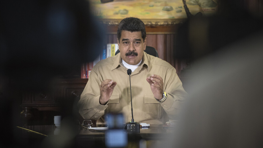 Nicolás Maduro sitting at his desk, speaking into a microphone