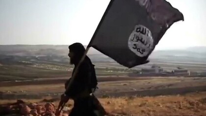 Miembro del estado islámico paseando su bandera por el desierto