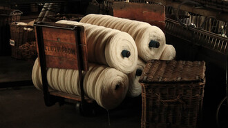 Several rolls of yarn made from plant-based fibers resting on a wooden cart, showcasing natural materials used in sustainable fashion