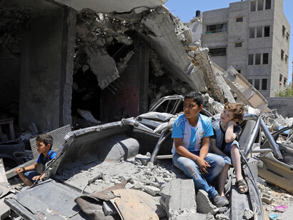 Viños palestinos ven a una banda tocar desde los escombros de un edificio destruido por los ataques aéreos israelíes. Fotografía: Mohammed Salem