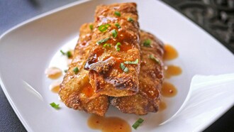 Crispy Philly cheesesteak egg rolls, drizzled with a sweet and savory glaze, garnished with fresh green onions — the perfect fusion of comfort and crunch