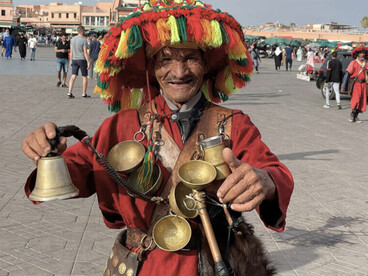 Sous les couleurs éclatantes de son chapeau et le tintement du métal à Marrakech, il avance comme une figure sortie d’un ancien conte marocain