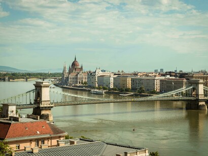 A historic brown and white building standing along the Danube River in Budapest, overlooking the water that divides and connects Buda and Pest, Budapest, Hungary