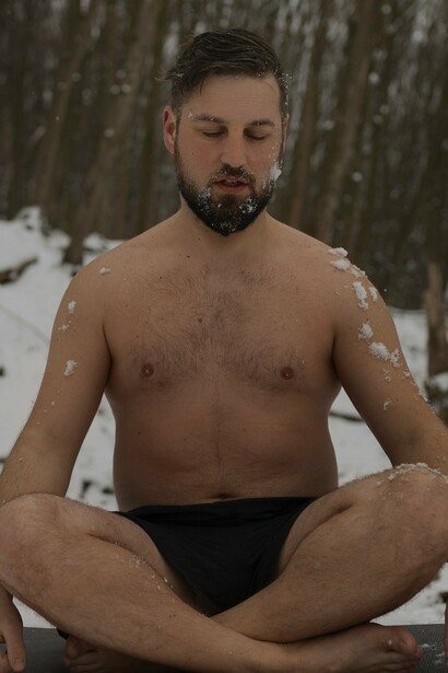 A man meditating in the snow using the cold as environmental stress, which helps to improve circulation, boost immunity, and enhance mental resilience—a testament to the benefits of controlled challenges in optimizing well-being