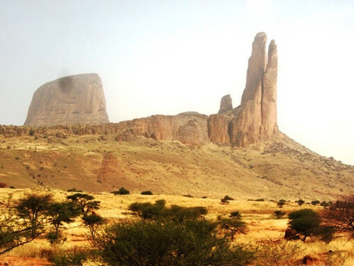 Entre ciel brûlant et terres ocre, la Main de Fatima domine l’horizon de Hombori au Mali, monument naturel où le désert semble avoir figé la pierre en plein mouvement