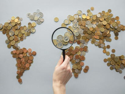 A magnifying glass examines the coins on the map