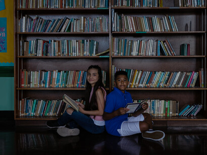 Two young students, sitting in a library, busy studying, to achieve great goals