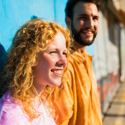 Amici sorridenti appoggiati al muro mentre guardano altrove