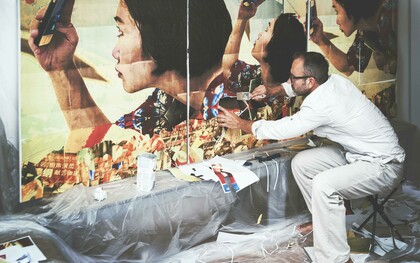 An artist paints a wall while working on the street