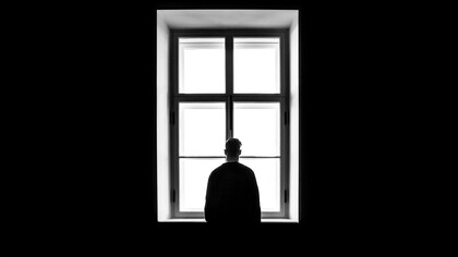Homem contemplando janela. A demarcação emocional é uma metáfora que nos convida a explorar os territórios internos da mente