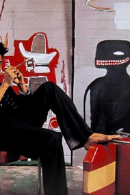 L'artista Jean-Michel Basquiat nel suo studio in Great Jones Street, New York, accanto all'opera 'Untitled' (1985)
