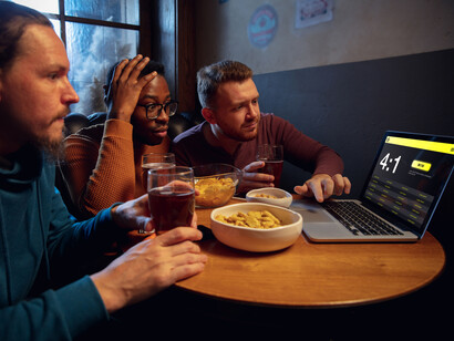 Three men huddled together watching betting sites
