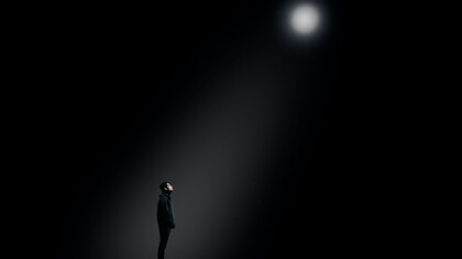 A man poised beneath a spotlight's glow, capturing a moment of dramatic intensity