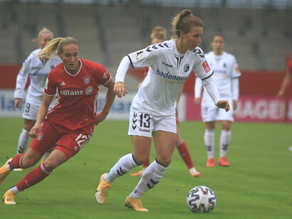 A dynamic photograph capturing women competing in a soccer game, representing female sports