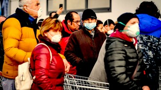 Decenas de personas con mascarillas hacen cola ante un supermercado en Italia