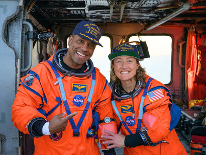 NASA astronaut Victor Glover (left) and NASA astronaut Christina Koch, sitting on a Navy MH-60 Seahawk