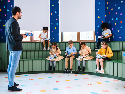 A teacher guiding children as they explore books together, representing how shared reading nurtures curiosity and lifelong learning