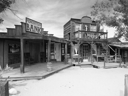 Pioneertown's preserved Western buildings, such as the bank and a saloon, stand against a backdrop of a partly cloudy sky