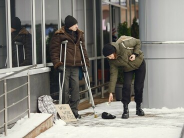 Winter city scene showing a woman helping a homeless man in need