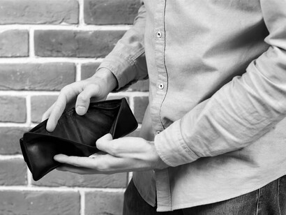 A man holding an empty wallet, symbolizing the loss of purchasing power and the economic insecurity many face due to Trump's policies