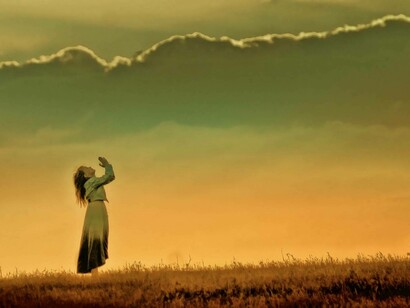 A young woman praying to heaven in hopes God will hear her call