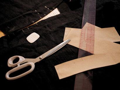 Fabric and tailoring tools arranged on a worktable, representing the precision and craftsmanship required to create quality garments