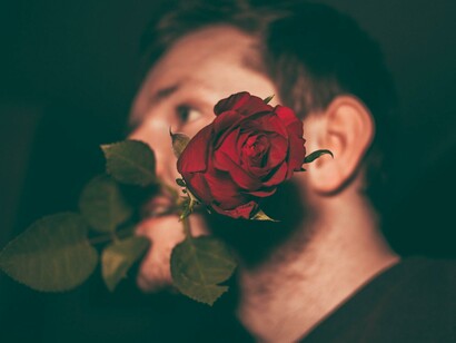 Um homem segura uma rosa entre os lábios