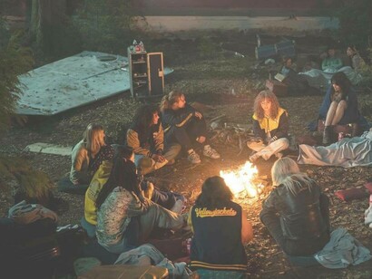The group from Yellowjackets huddled around a fire in the woods