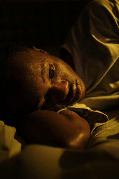 A Gen Z youth scrolling on his phone in bed captures the toll of the pandemic—screen dependence, loneliness, and mental strain