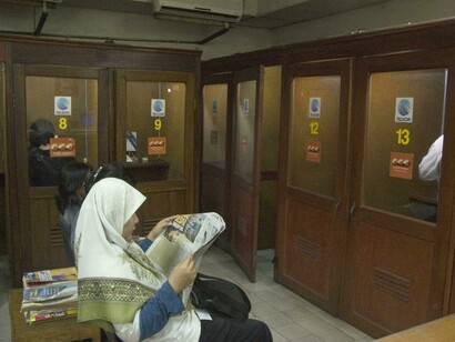 Una mujer lee un periódico mientras espera su turno en un locutorio para llamar a su país