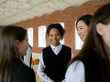 A group of students in school uniforms chatting in the basketball court