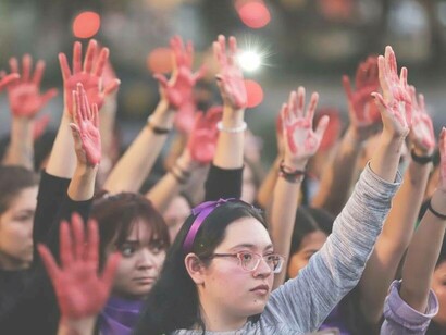 Women raising a bloodied hand to demonstrate their cause against femicide in Puebla, Mexico