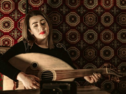 A woman immersed in the melodies of the oud, symbolising the preservation of Shaabi traditions across generations