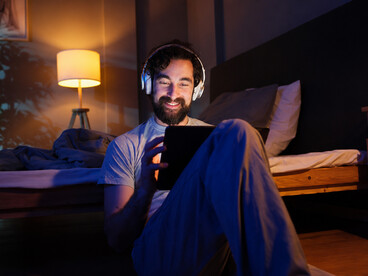 Young man wearing headphones while relaxing and watching a movie on his tablet