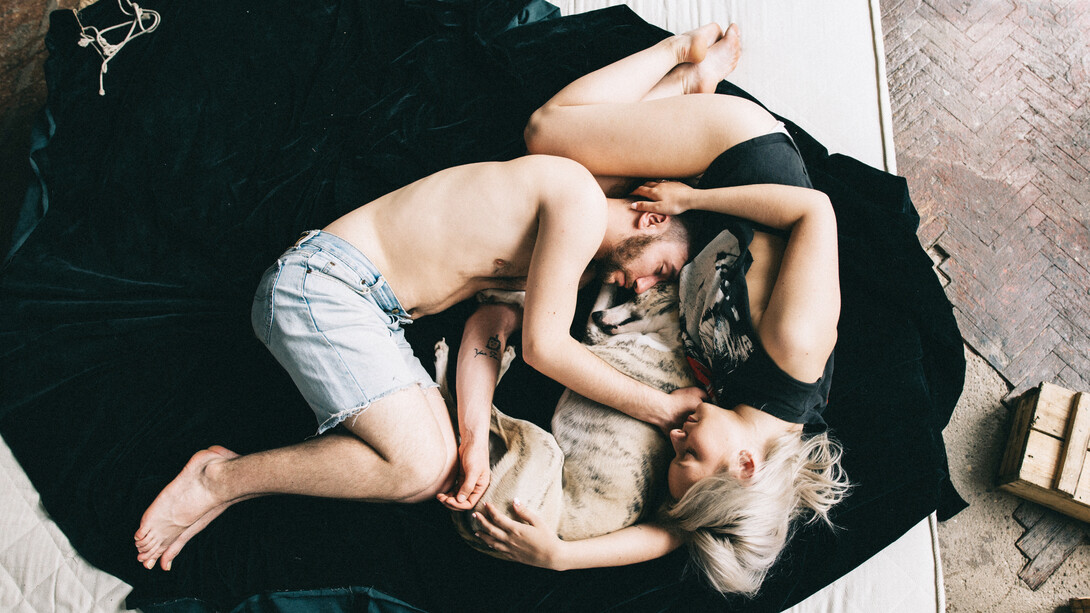 A couple curls up with their dog for some sleep
