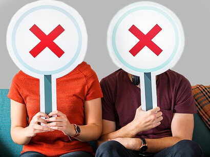 A couple sits on a couch, holding vote icons to symbolize red and green flags in their relationship