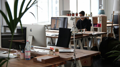 A man sits in front of a computer, surrounded by the clean lines and simplicity of a minimalist office space in Berlin, Germany
