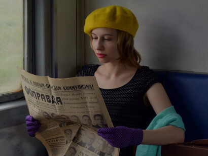 Experience the tranquility of a young lady seated with a Russian newspaper and suitcase aboard a train in Russia, capturing the essence of travel and cultural immersion