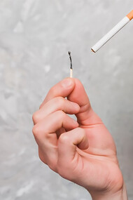 Close-up of a woman blowing on a matchstick held by her boyfriend, who has a cigarette in his mouth, with an intimate and casual vibe