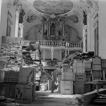 An American Army soldier inspects German loot found in the German town Ellingen, 1945