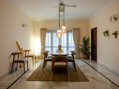A neatly arranged and illuminated dining room with a table and chairs