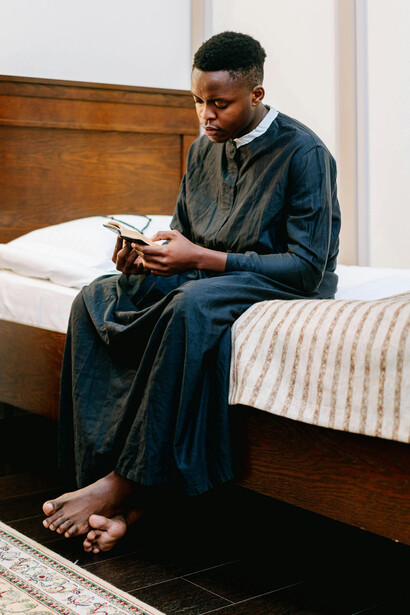 A man dressed in black stands holding a Bible, praying quietly