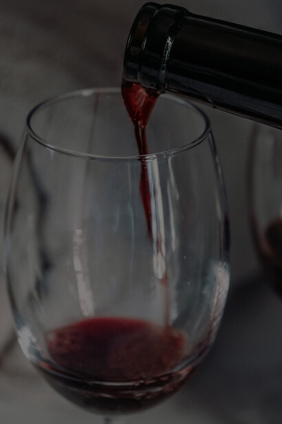 An individual pouring wine into a pristine, transparent wine glass