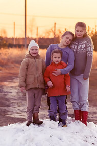 Two children stand on snow-covered ground during the daytime, playing on a snowdrift at a farm near Moscow, USSR